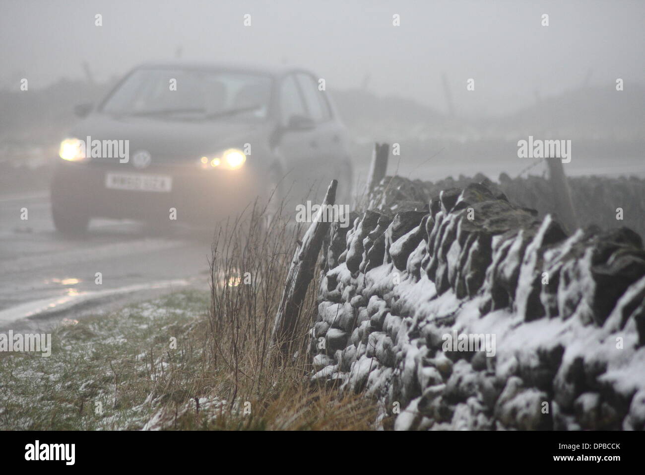 Il Peak District, Derbyshire, Regno Unito. 11 gennaio 2014. Condizioni invernali sulla A6187 vicino a Castleton realizzato per difficili condizioni di guida dopo una notte di nevicata hit tratti di alta massa nel Derbyshire's Peak District. Credito: Matthew Taylor/Alamy Live News Foto Stock
