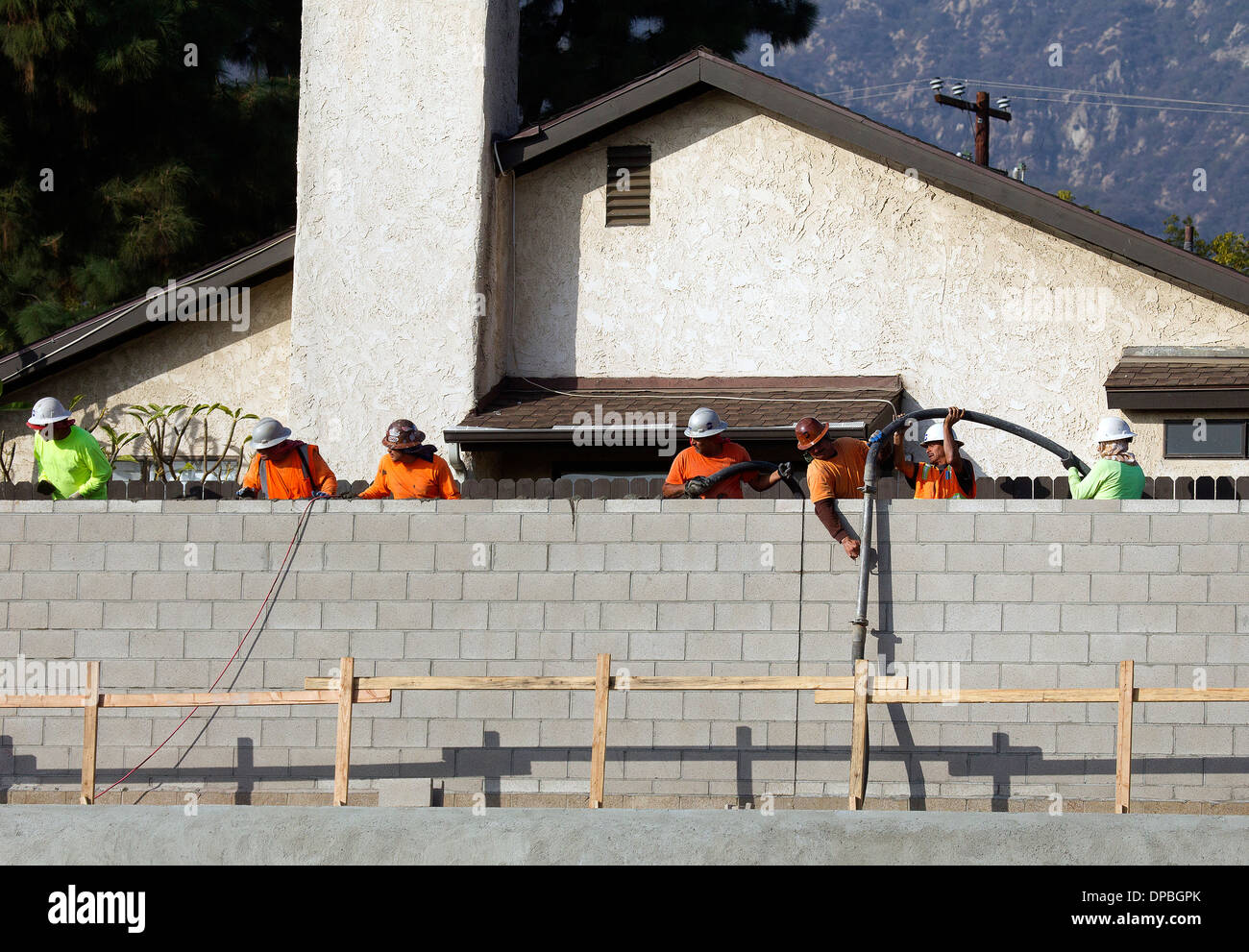 Operai edili che pompano calcestruzzo nella parete a blocchi Foto Stock