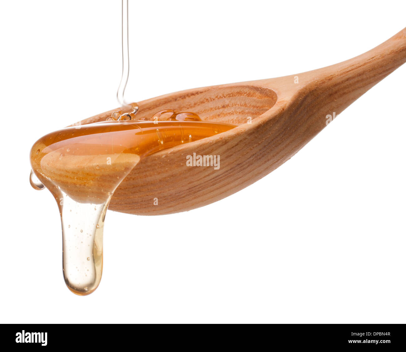 Il miele il gocciolamento da un miele di legno isolata del bilanciere su sfondo bianco intaglio Foto Stock