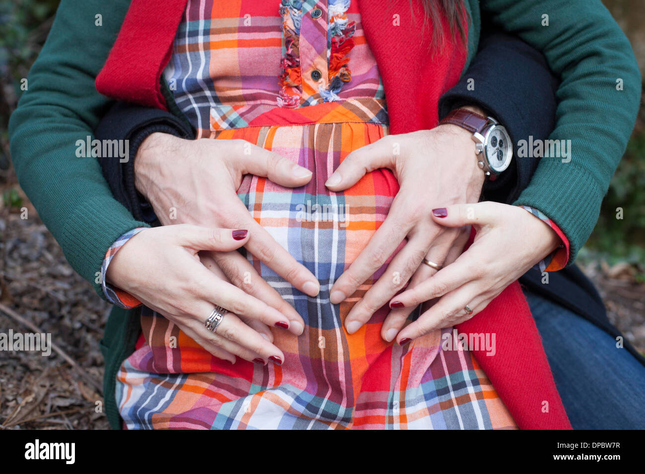 Le mani del padre e della madre sul bambino ventre formando un cuore. Foto Stock