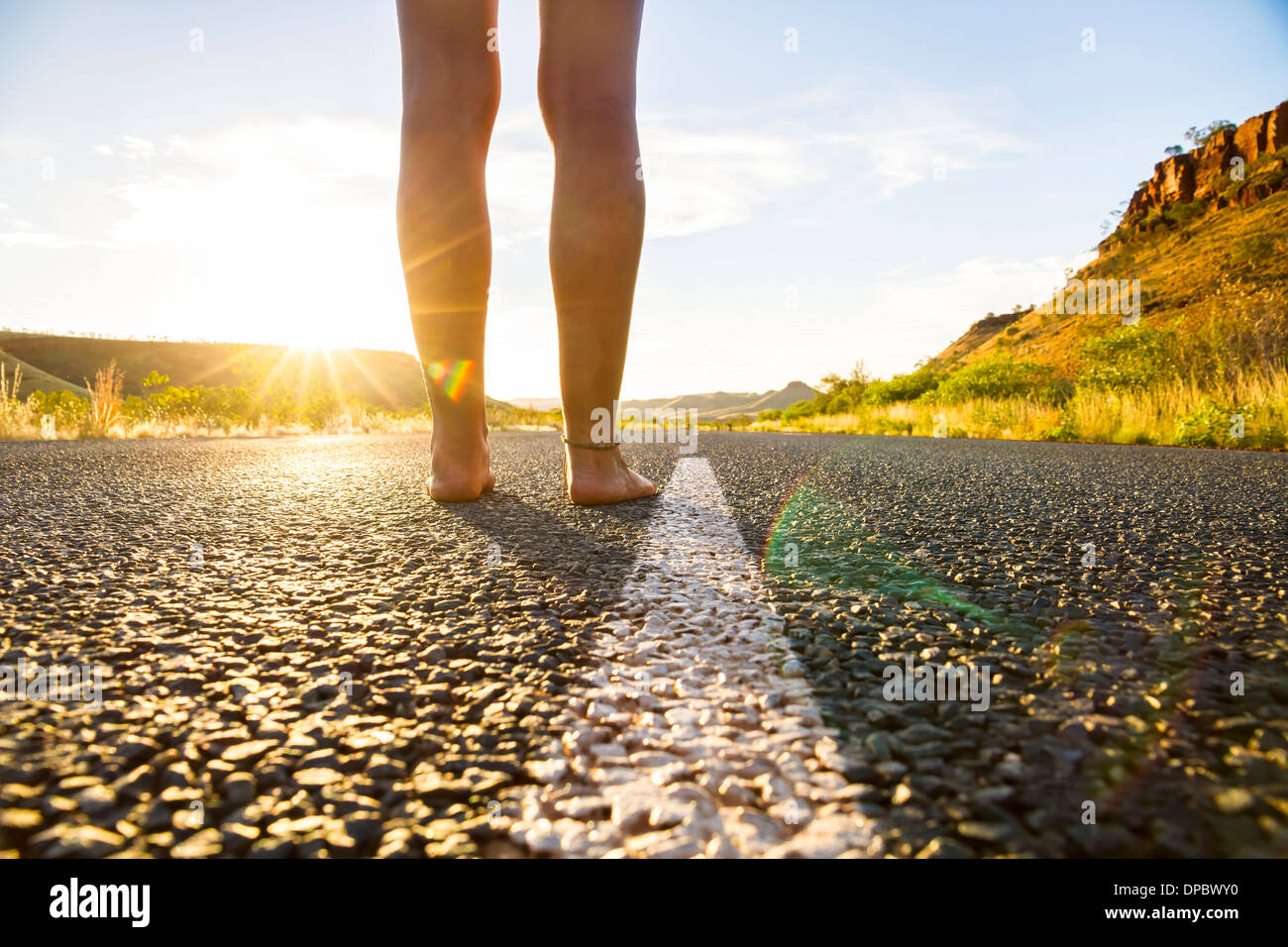 Australia, Australia occidentale, giovane donna a piedi nudi sulla strada vuota Foto Stock