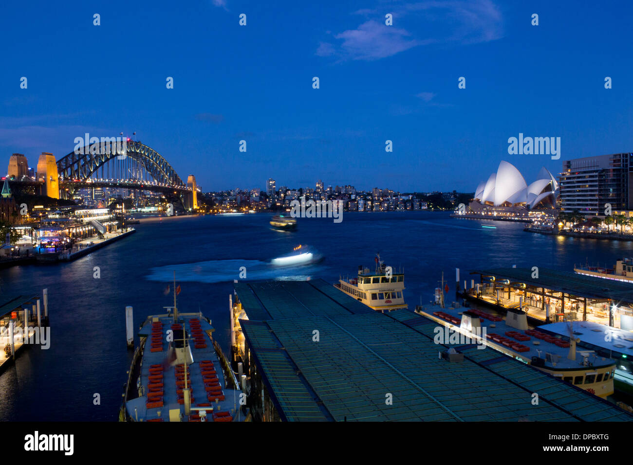 Il Circular Quay di notte con i traghetti in arrivo e in partenza, Harbour Bridge e Opera House Sydney New South Wales NSW Australia Foto Stock