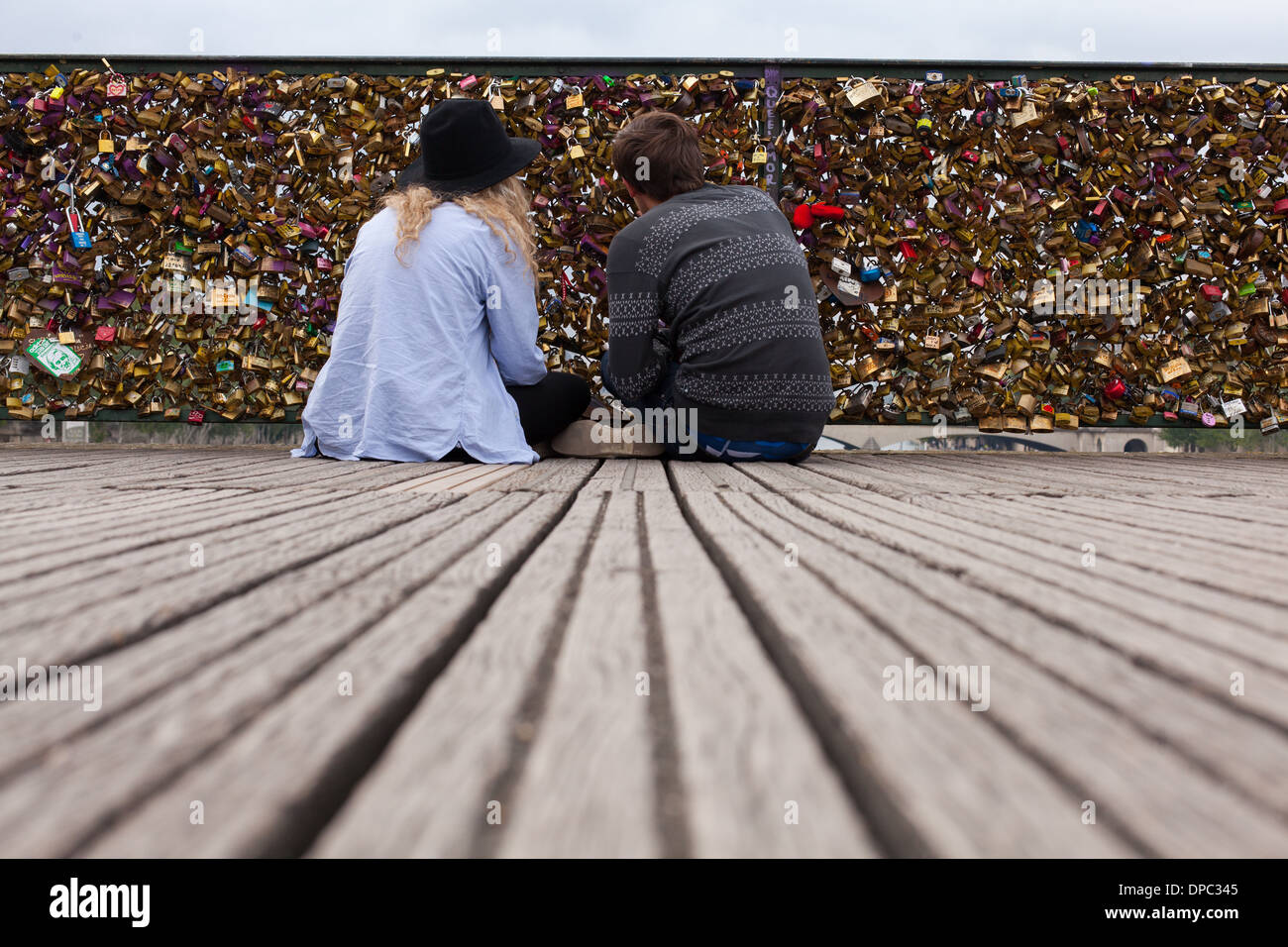 Parigi. La Francia. Due amanti di sedersi di fronte il loro amore a gancio serratura. Foto Stock