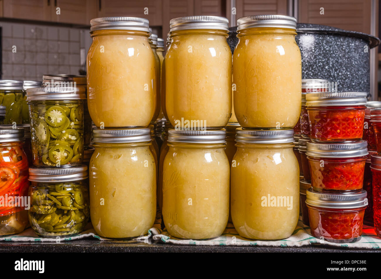 Home conserve di salsa di mele, peperone e pomodoro marmellata impilati sul bancone cucina con acqua calda canner in background Foto Stock