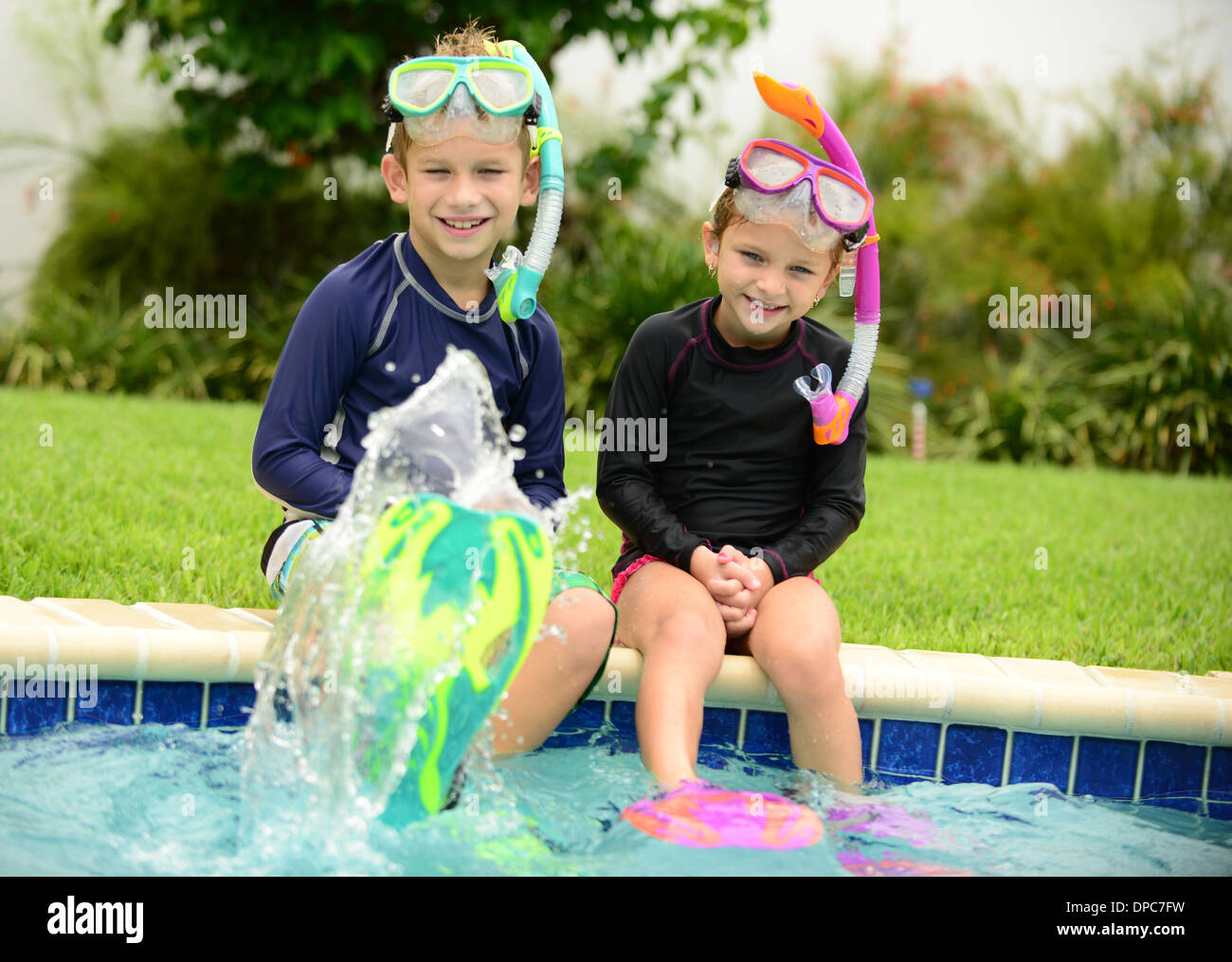 Due bambini di spruzzi d'acqua con pinne nuoto in piscina Foto stock - Alamy