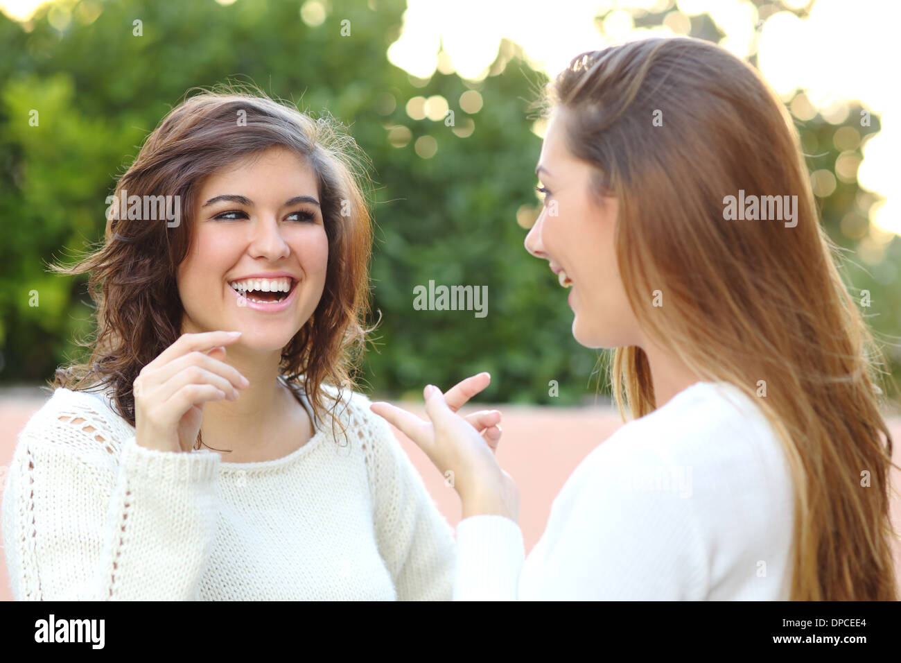 Due giovani donne parlando felice outdoor Foto Stock