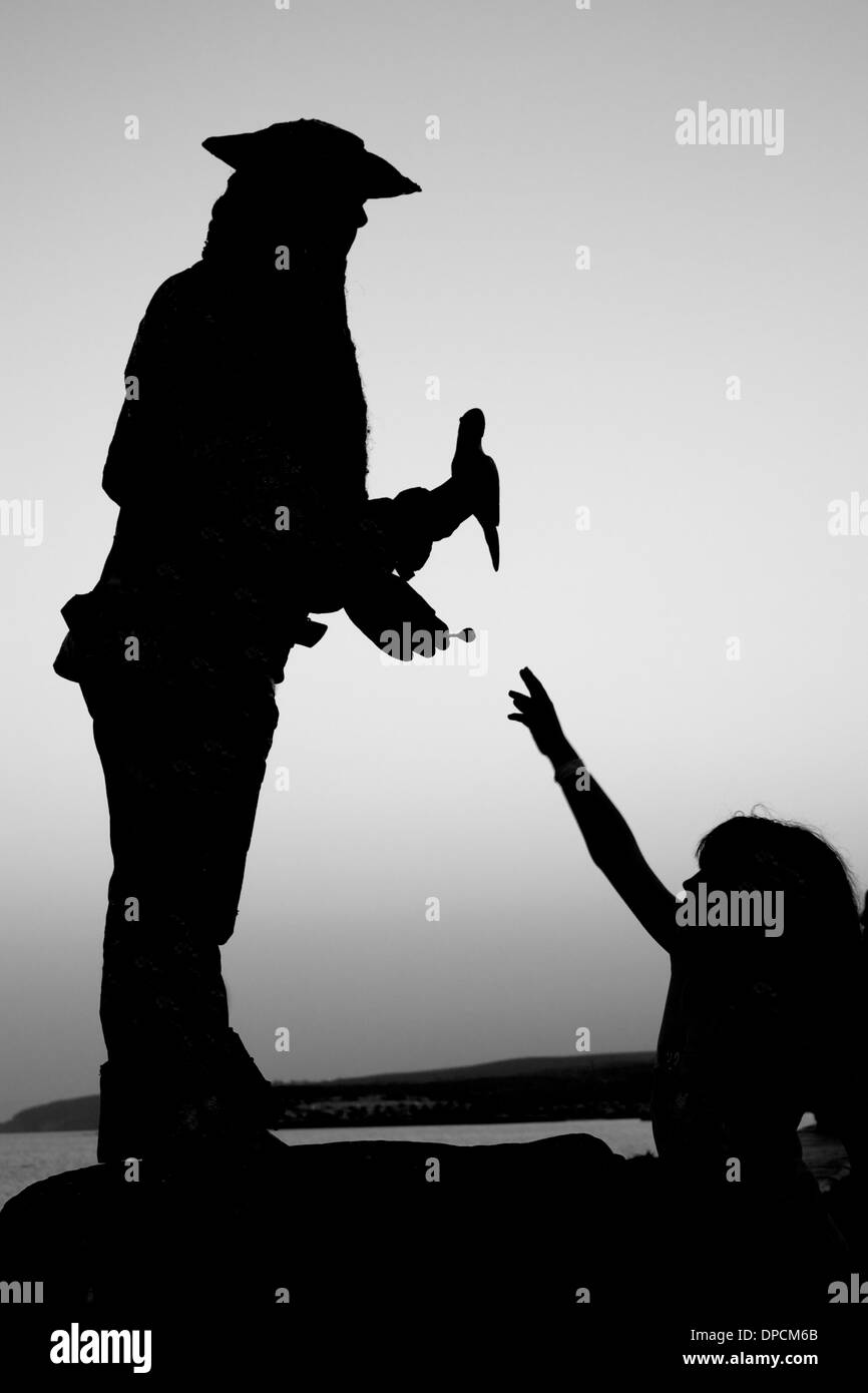 Silhouette di un bambino riceve un dolce da un pirata Foto Stock
