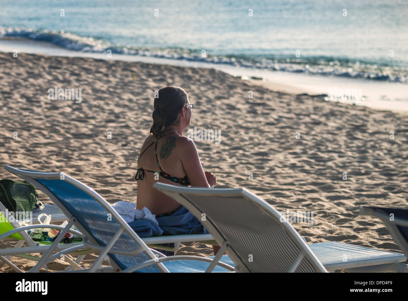 Una donna nel suo inizio 40s si trova sulla spiaggia di castelli di sabbia nel suo costume da bagno e si affaccia sul mare di St. Croix, U.S. Isole Vergini. Foto Stock