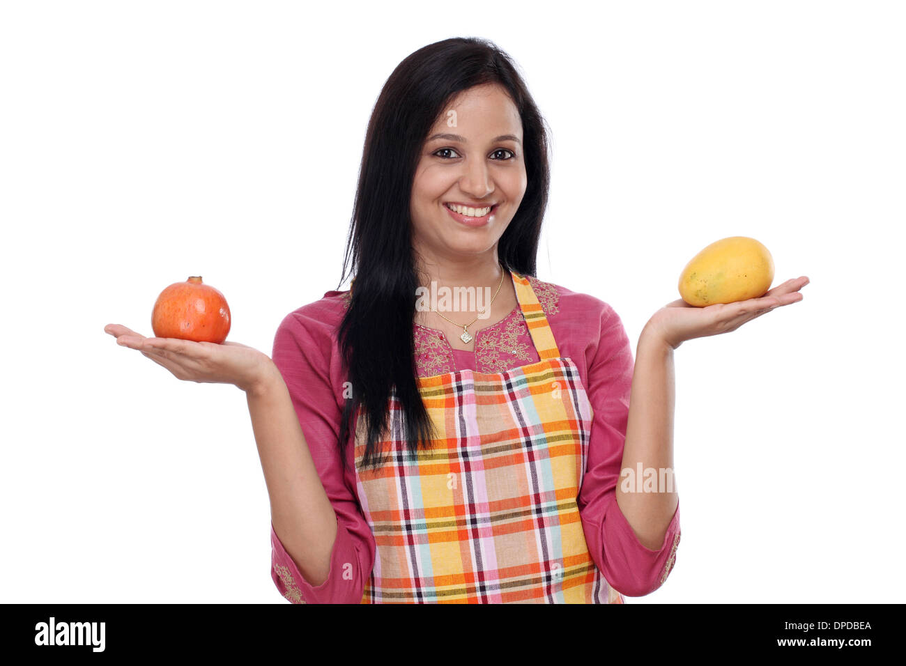 Giovane donna indossa Grembiule da cucina e frutti di contenimento Foto Stock