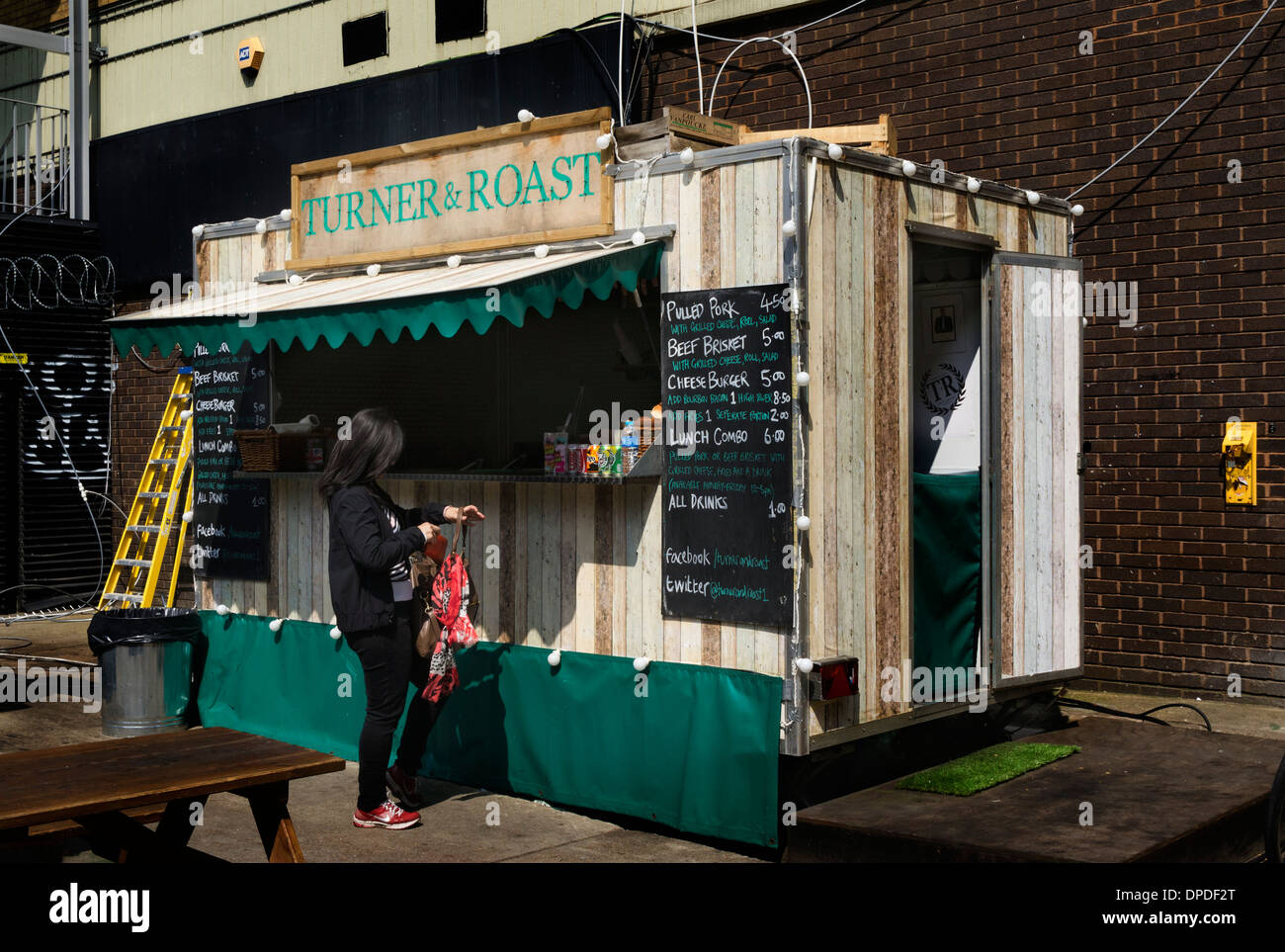 Signora giovane comprare cibo a Turner e arrosto di fast food stand in Brick Lane area, East London E1 REGNO UNITO Foto Stock