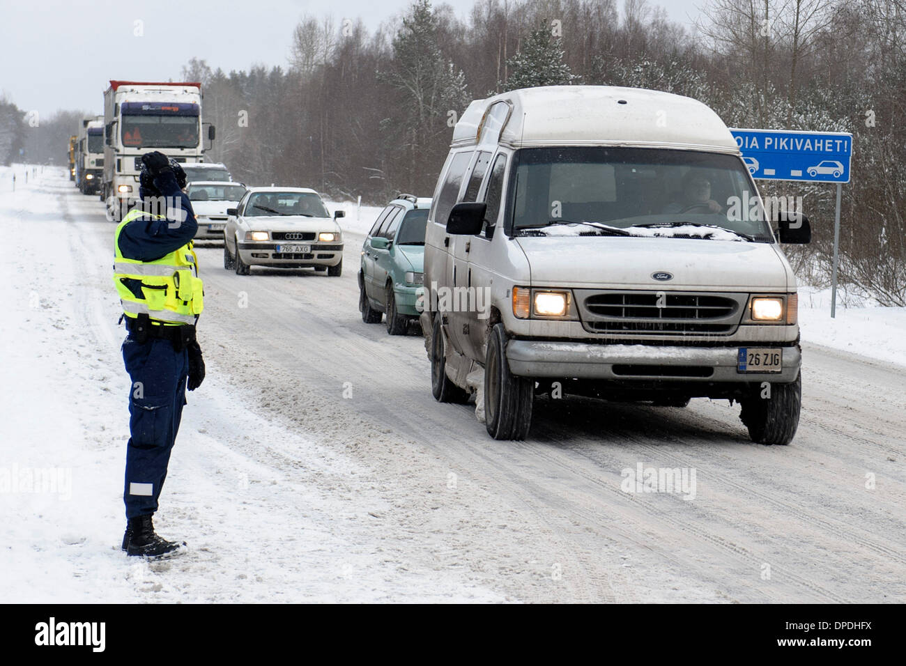 Narva. Xiii gen, 2014. Un funzionario di polizia si erge sul dovere guardare la condizione di traffico nel nordest dell'Estonia Gen 13, 2014. La mattina tempesta di neve ha rallentato le principali E20 collegamento autostradale tra Estonia-Russia border e Tallinn con molti incidenti stradali. Credito: Sergei Stepanov/Xinhua/Alamy Live News Foto Stock