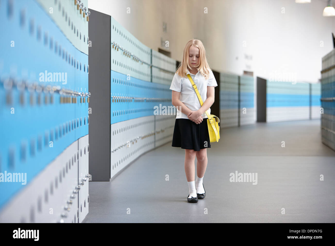 Infelice schoolgirl camminare da solo nel corridoio della scuola Foto Stock
