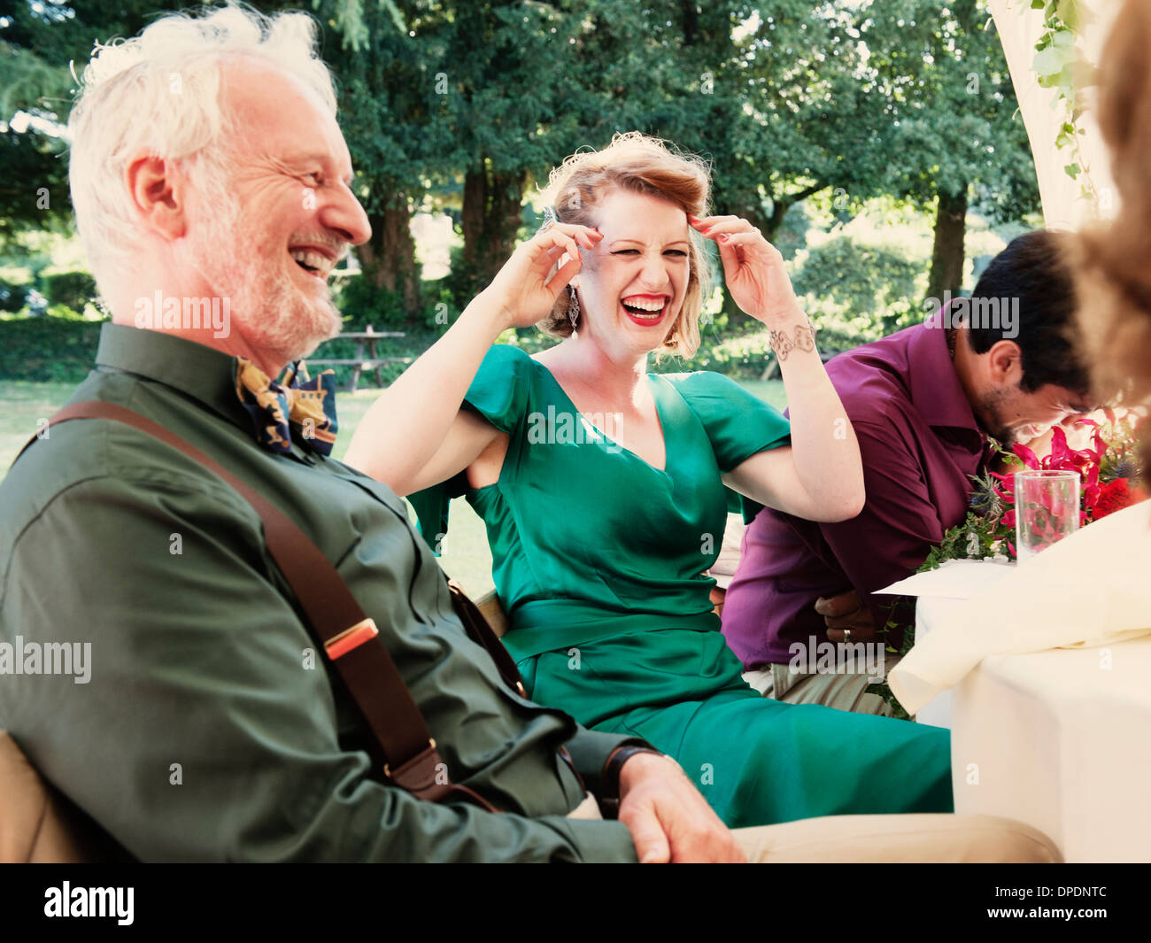 Gli sposi con i genitori di ridere a ricevimento di nozze Foto Stock