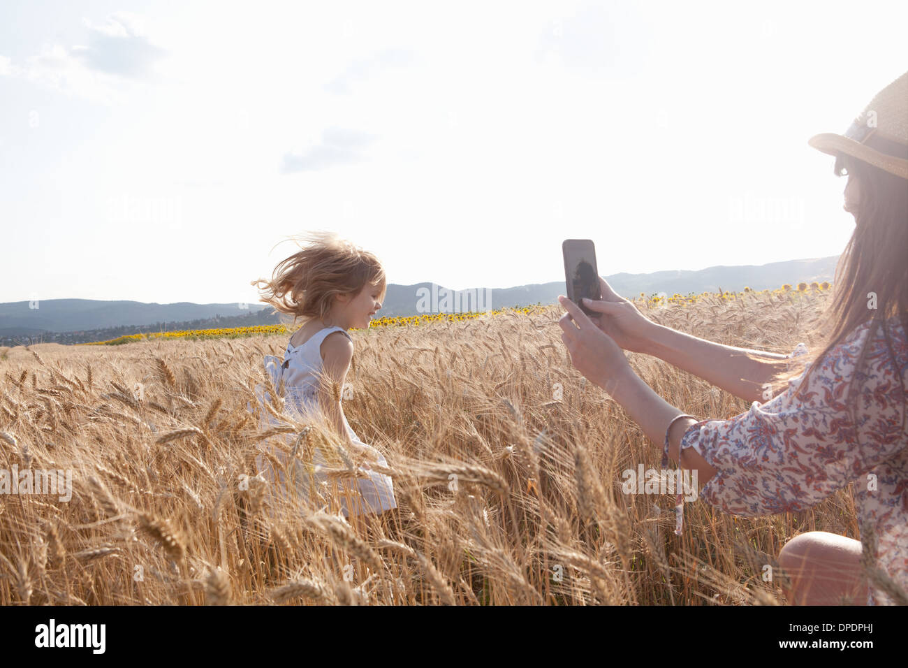 Madre fotografare la ragazza che corre attraverso il campo di grano Foto Stock