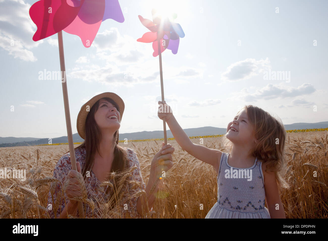 Madre e figlia nel campo di grano tenendo il mulino a vento Foto Stock