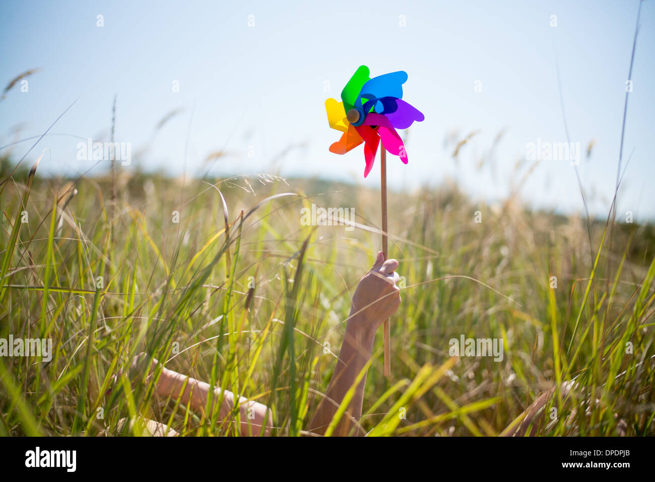 Donna sdraiata in erba lunga tenendo il mulino a vento Foto Stock