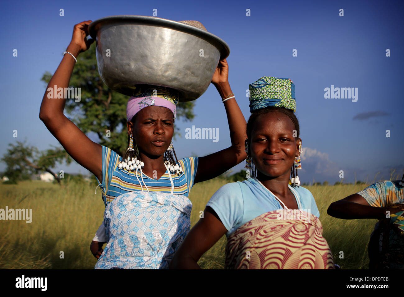 Le donne africane sulla strada per il mercato con la produzione di trasportati in ceste, bacino e sacchi Foto Stock