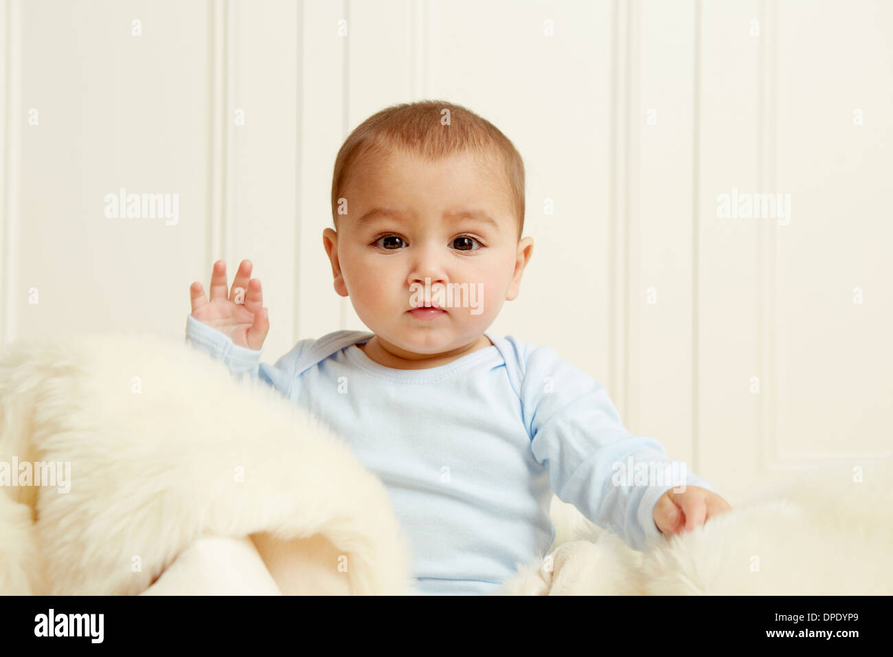 Baby sitter sul tappeto di pelle di pecora Foto Stock