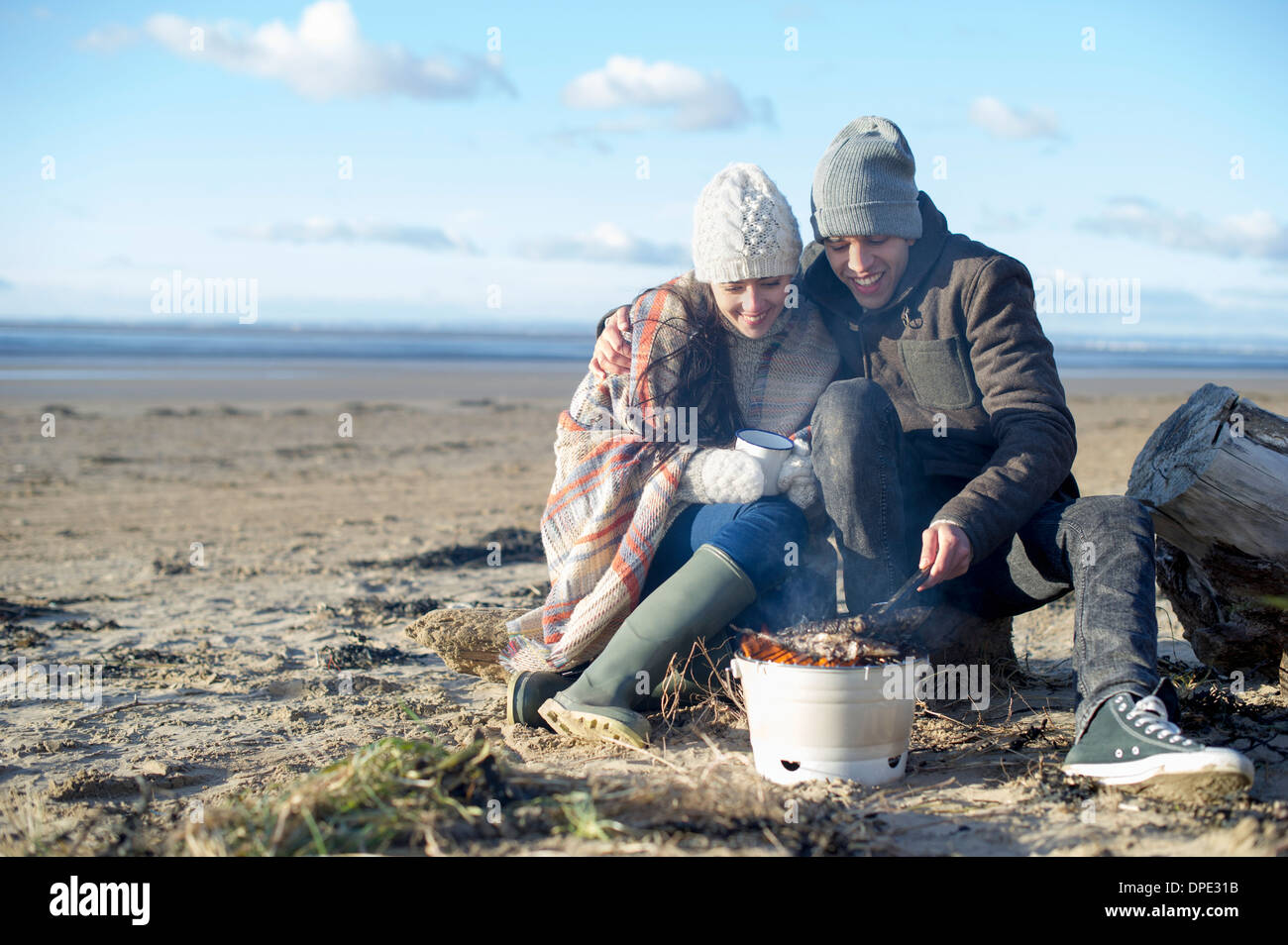 Coppia giovane avente il barbecue sulla spiaggia, Brean Sands, Somerset, Inghilterra Foto Stock