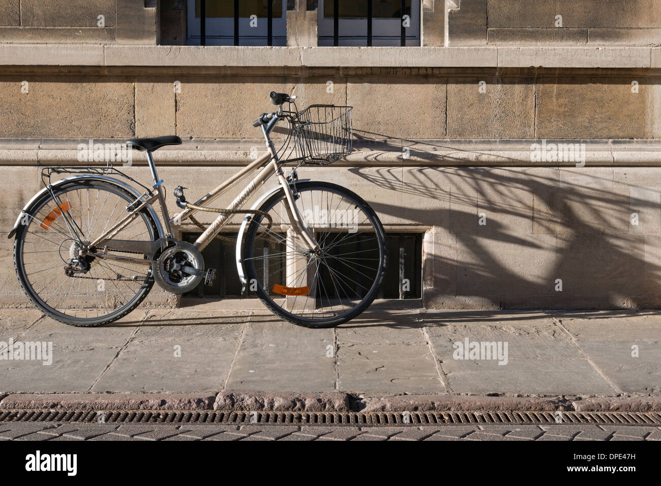 Una bicicletta si appoggia contro un vecchio muro di College di Cambridge Regno Unito. La città è conosciuta come la città del ciclo. Foto Stock
