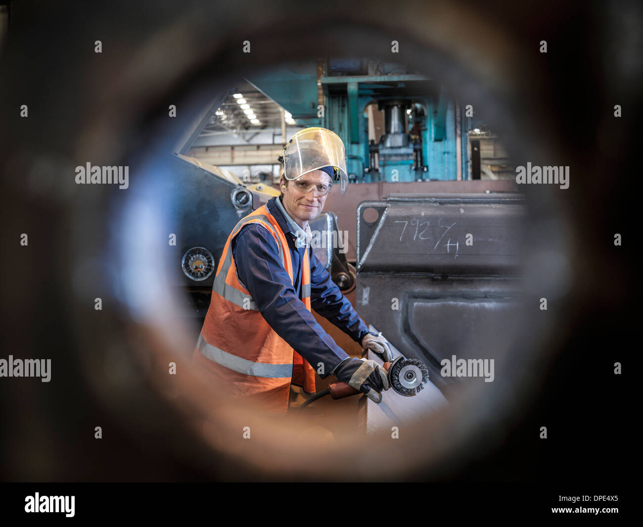 Ritratto di ingegnere in fabbrica visto attraverso il foro in acciaio Foto Stock
