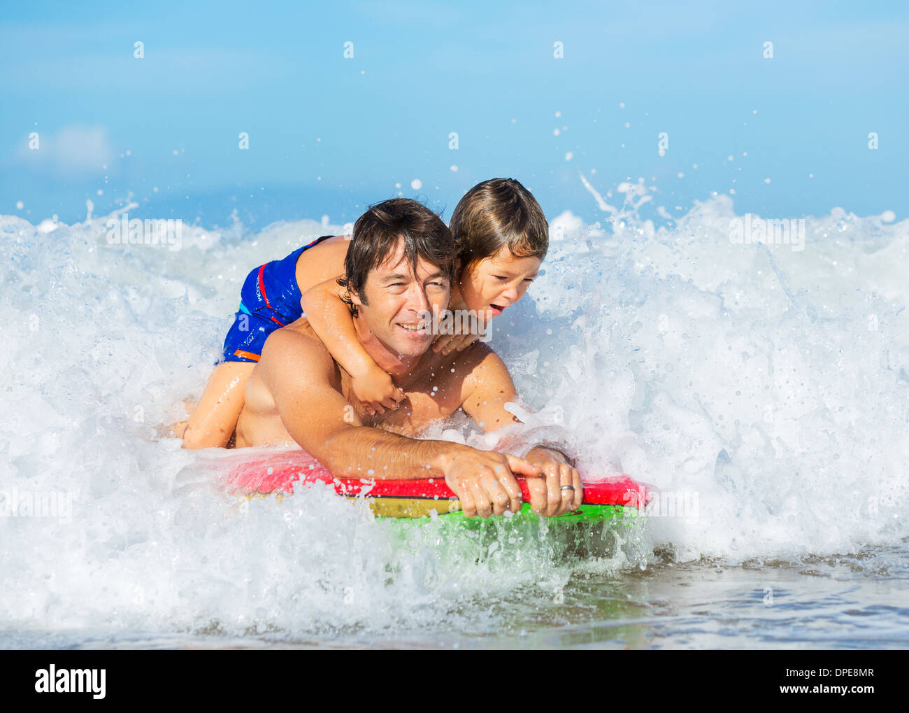 Padre e Figlio Surf Tandem compresi la cattura delle onde oceaniche, spensierato divertimento felice sorridente lifestyle Foto Stock