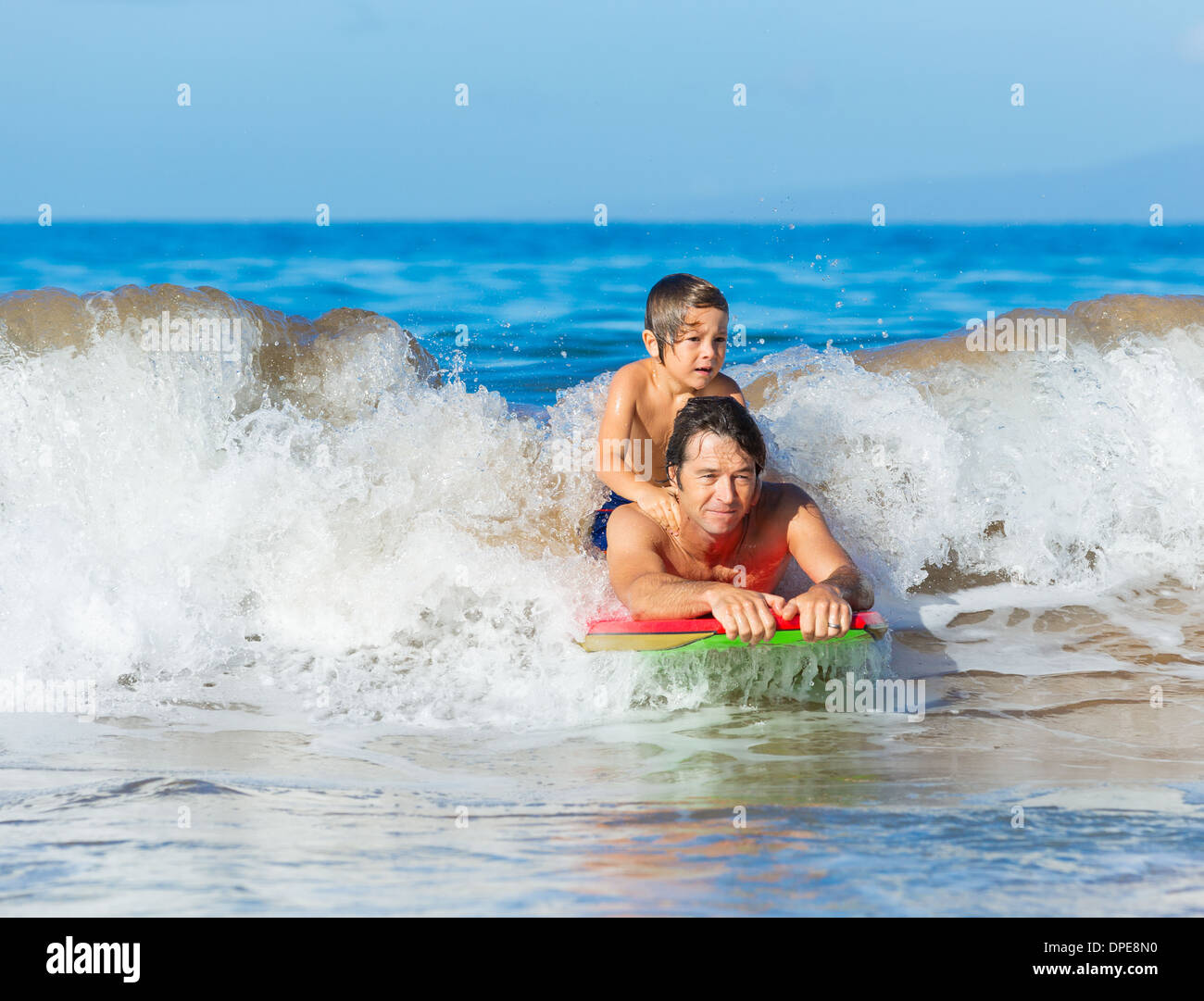 Padre e Figlio Surf Tandem compresi la cattura delle onde oceaniche, spensierato divertimento felice sorridente lifestyle Foto Stock