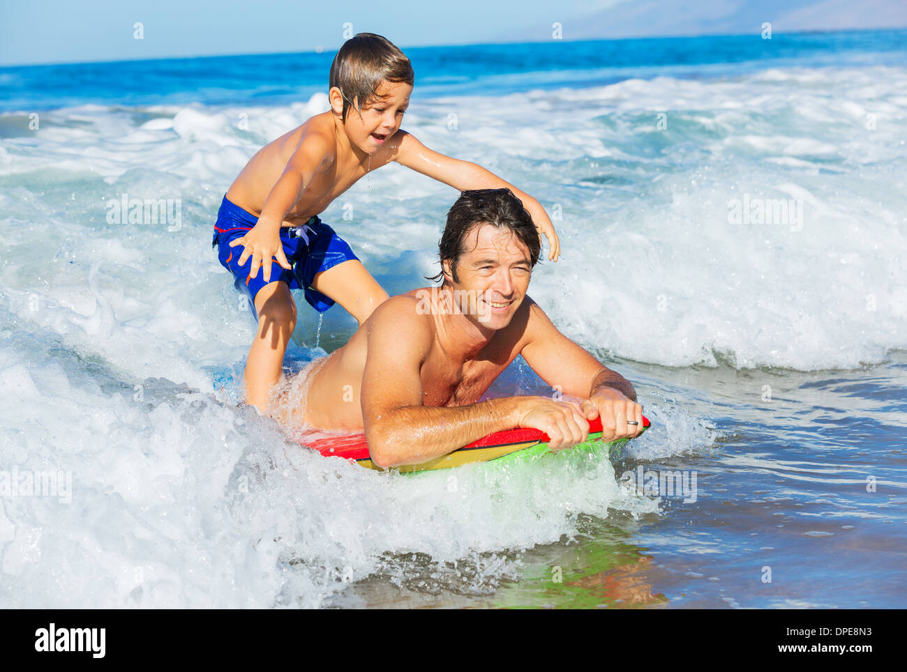 Padre e Figlio Surf Tandem compresi la cattura delle onde oceaniche, spensierato divertimento felice sorridente lifestyle Foto Stock