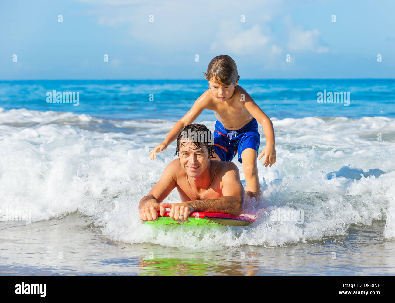 Padre e Figlio Surf Tandem compresi la cattura delle onde oceaniche, spensierato divertimento felice sorridente lifestyle Foto Stock