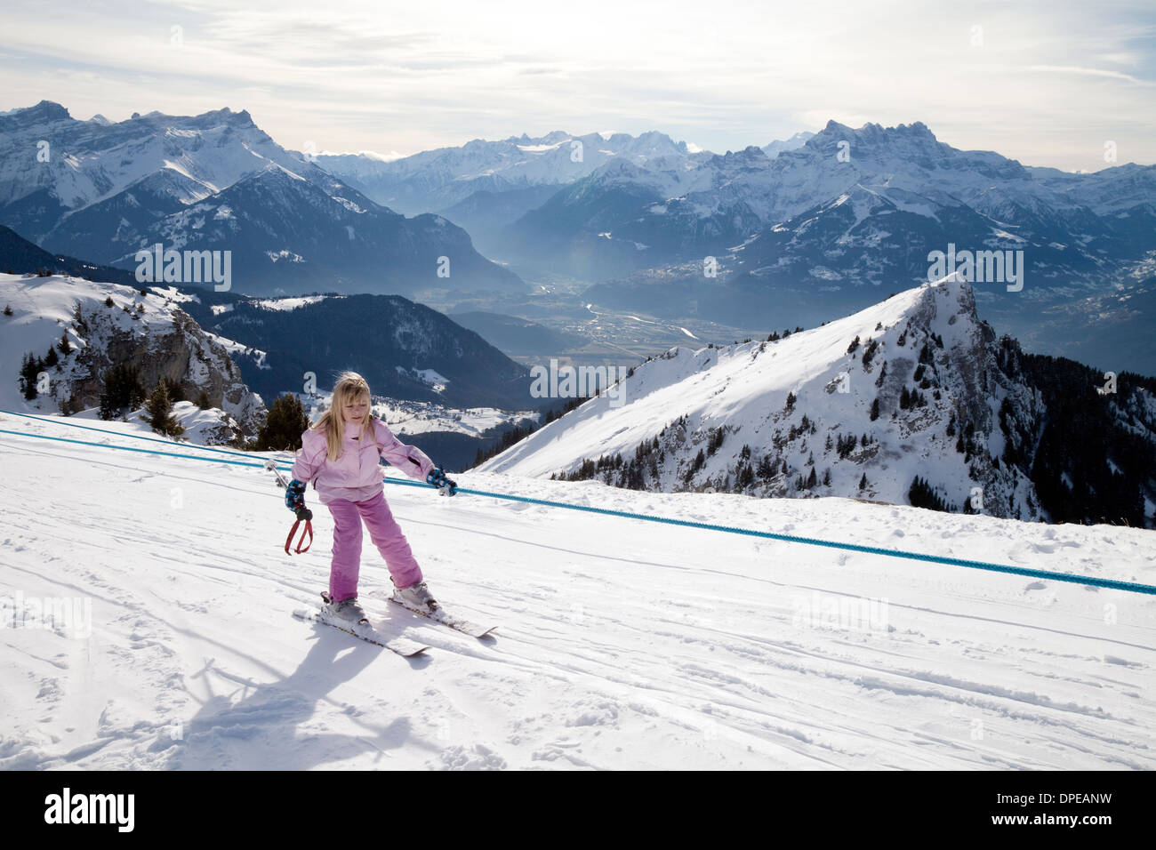 Un giovane bambino sci, utilizzando un drag lift non indossa un casco da sci, alpi svizzere, Svizzera, Europa Foto Stock