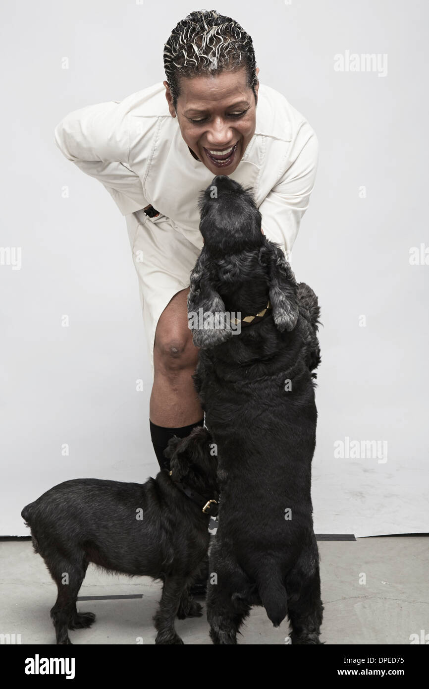 Studio shot di donna matura a giocare con i cani in pet Foto Stock
