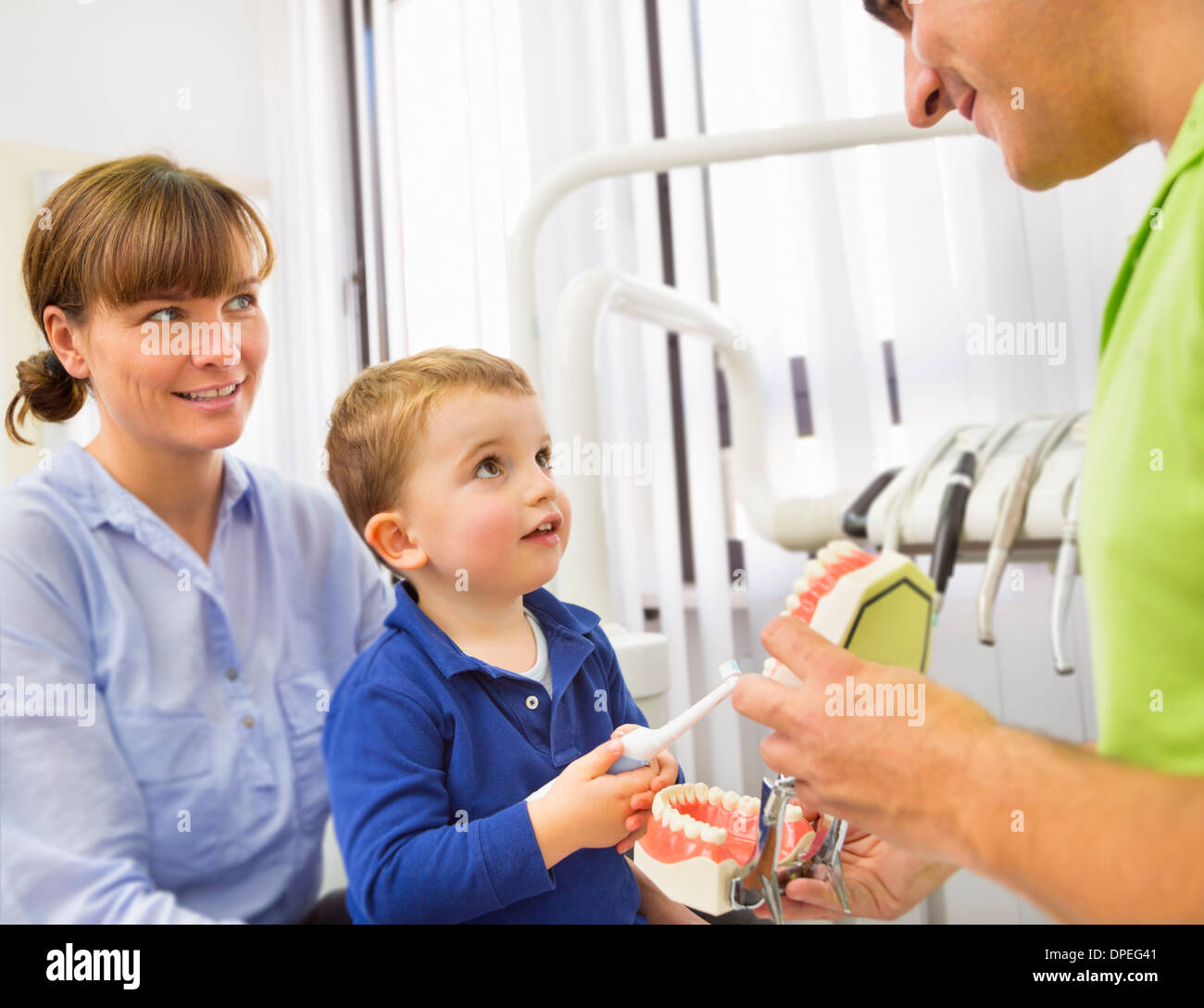 Dentista ragazzo di insegnamento sulle madri giro come spazzola denti Foto Stock