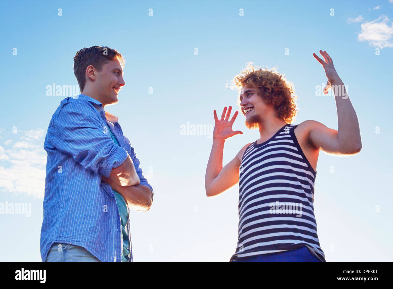 Due amici maschi godendo di conversazione in presenza di luce solare Foto Stock