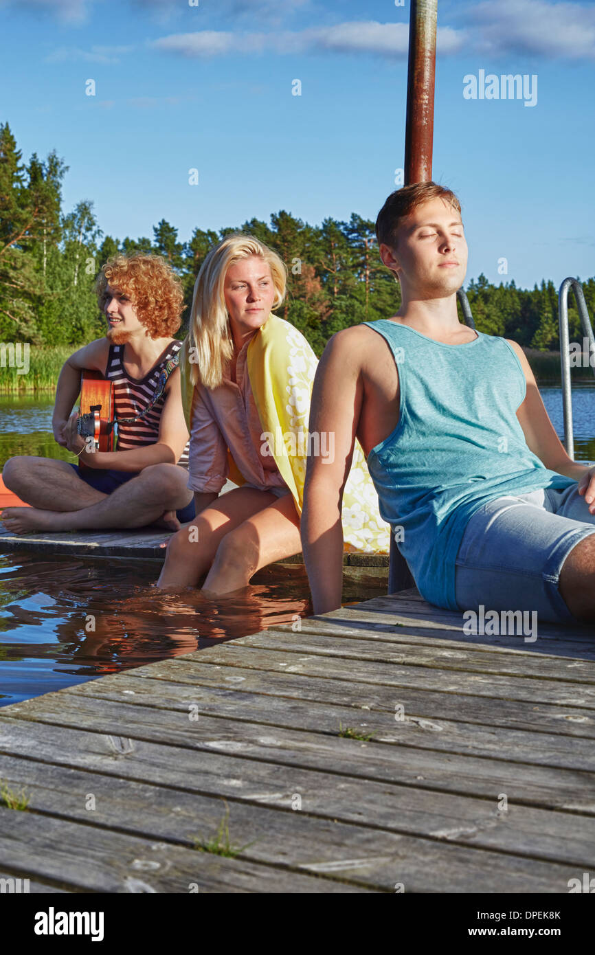 Tre giovani amici adulti rilassante sul molo, Gavle, Svezia Foto Stock