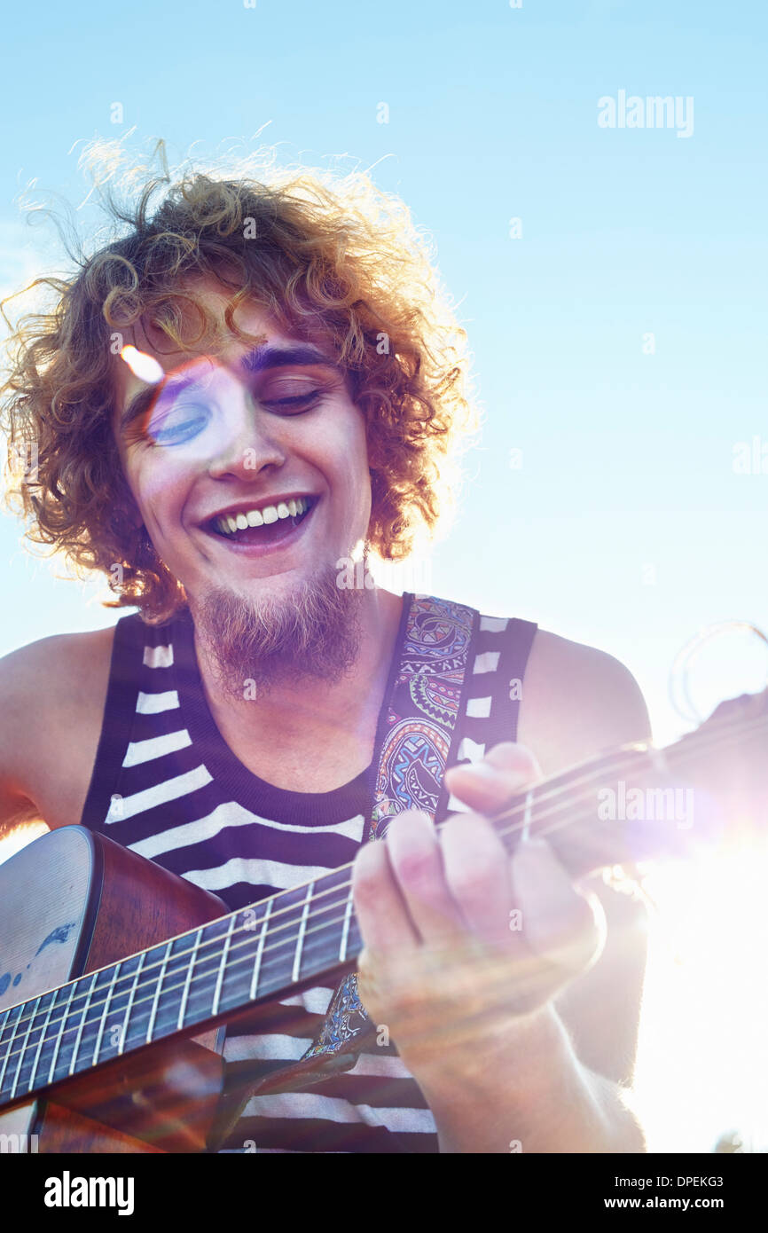 Giovane uomo a suonare la chitarra nella luce del sole Foto Stock