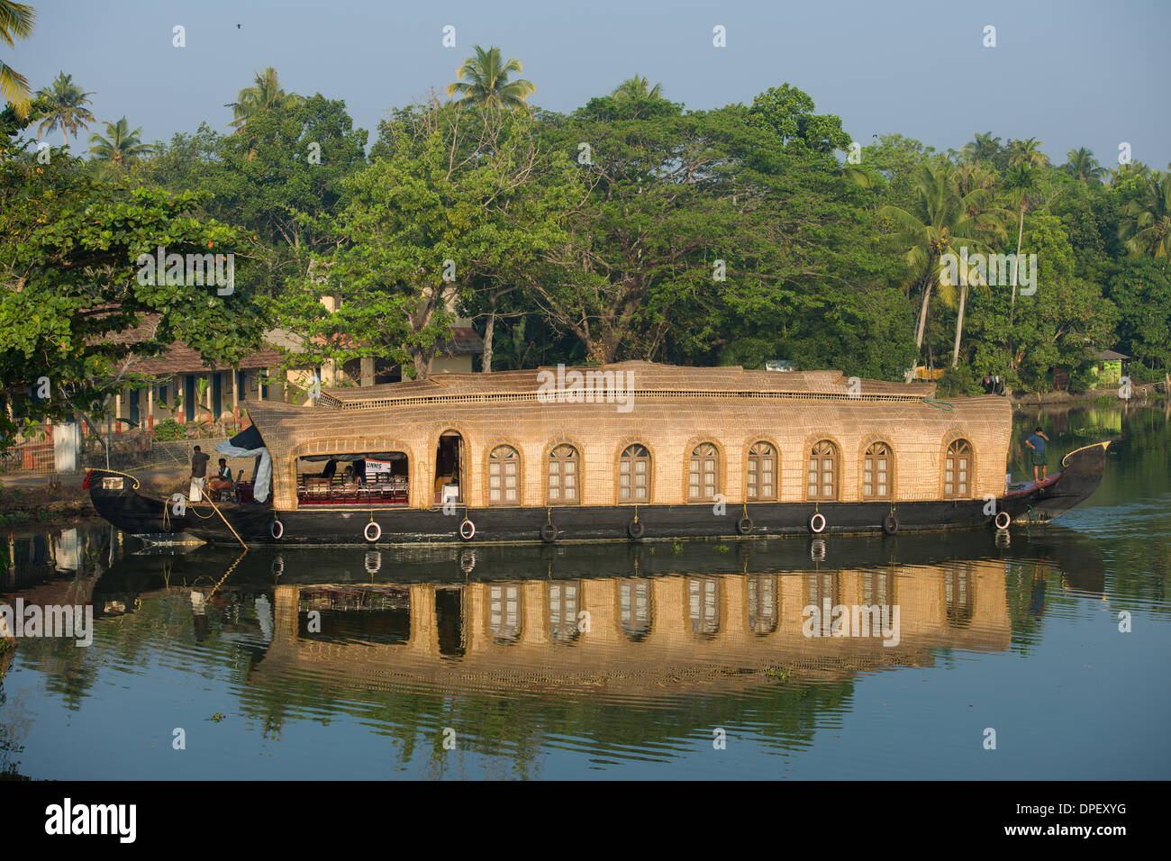 Appartamenti keralesi chiatta da riso houseboat (Kettuvallams) riflesso in una via navigabile a Kumarakom, Kottayam Kerala, India Foto Stock
