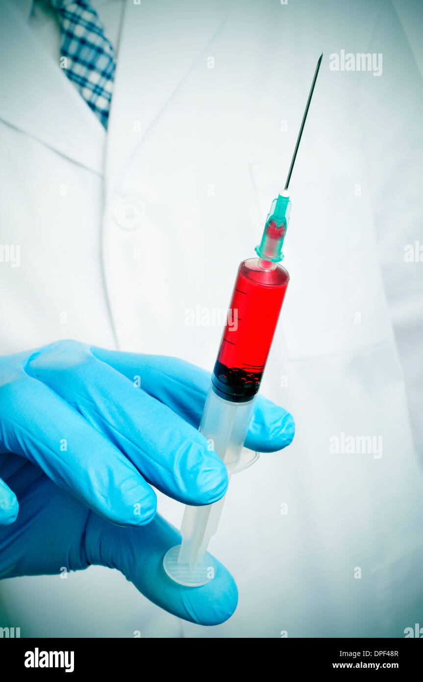 Un Dottore che indossa guanti medici titolari di una siringa con il sangue Foto Stock