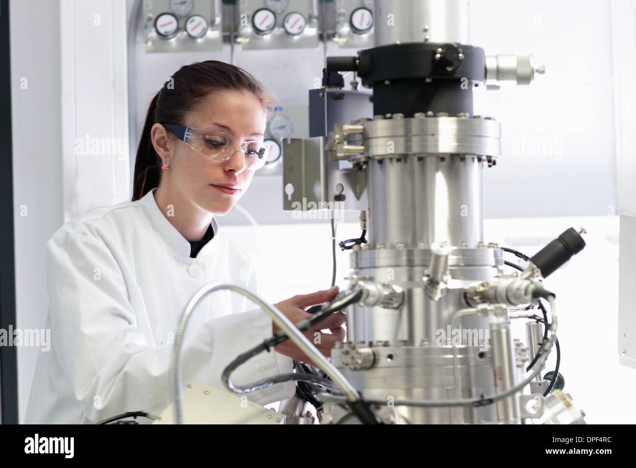 Donna scienziato operativo apparecchiature scientifiche in laboratorio Foto Stock