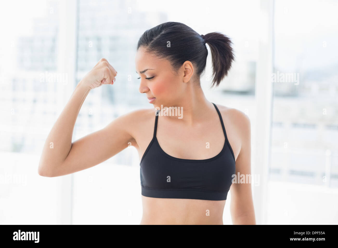 Forte dai capelli scuri modello in sportswear parti i suoi muscoli Foto Stock