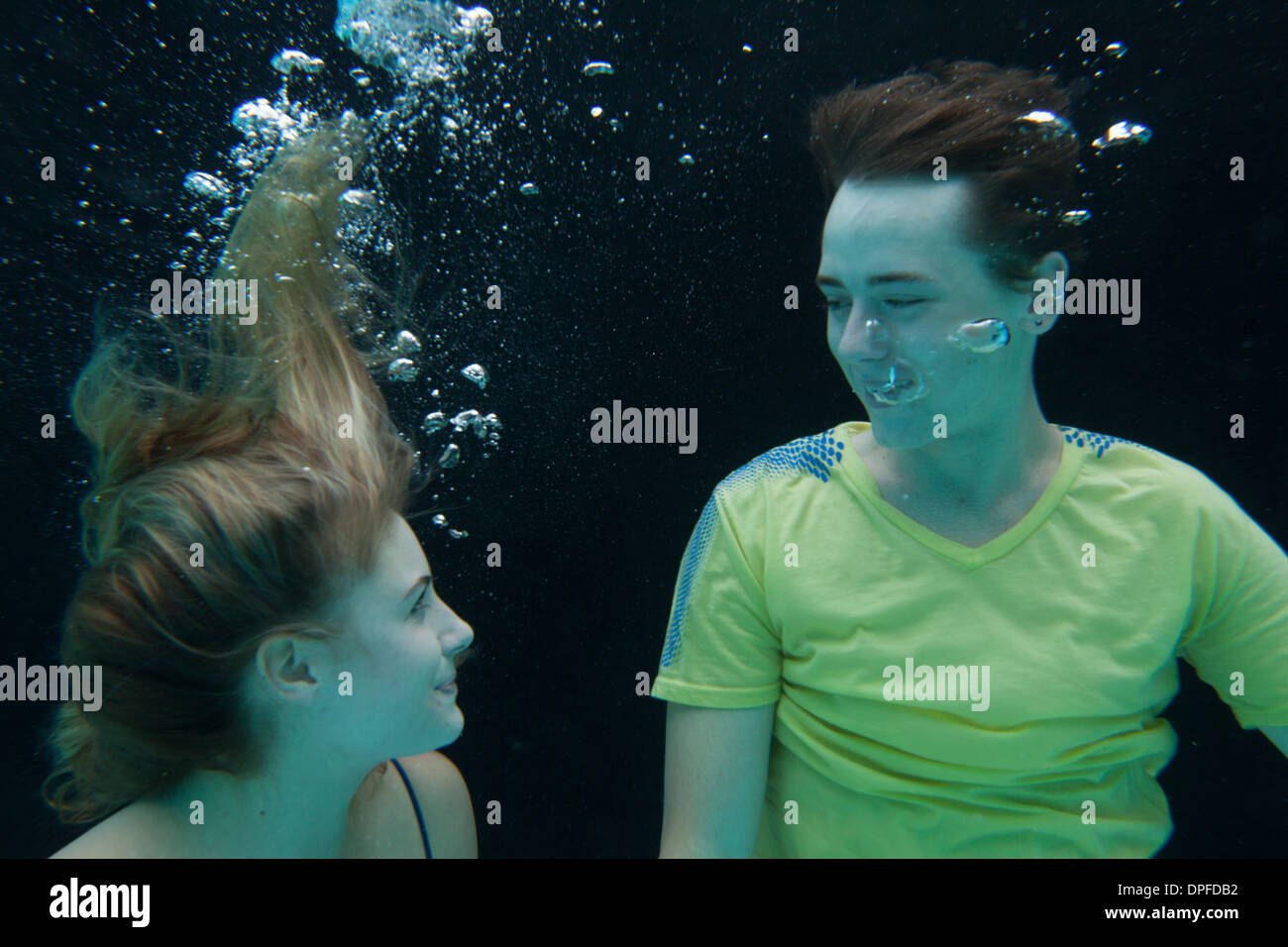 Coppia giovane completamente vestito subacquea flottante Foto Stock