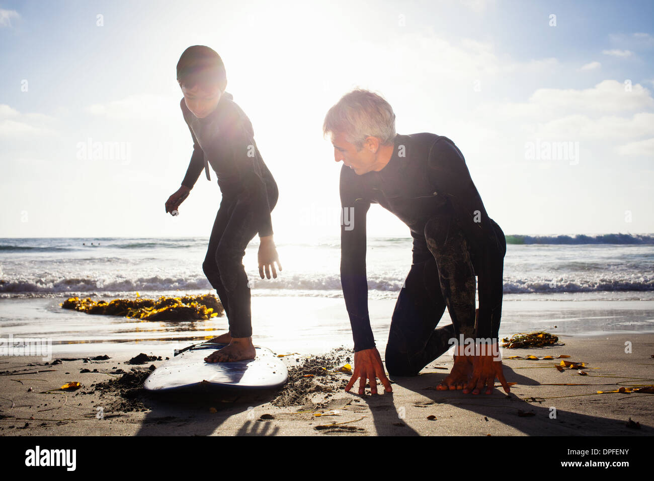 Padre e figlio a fare pratica con la tavola da surf sulla spiaggia, Encinitas, CALIFORNIA, STATI UNITI D'AMERICA Foto Stock