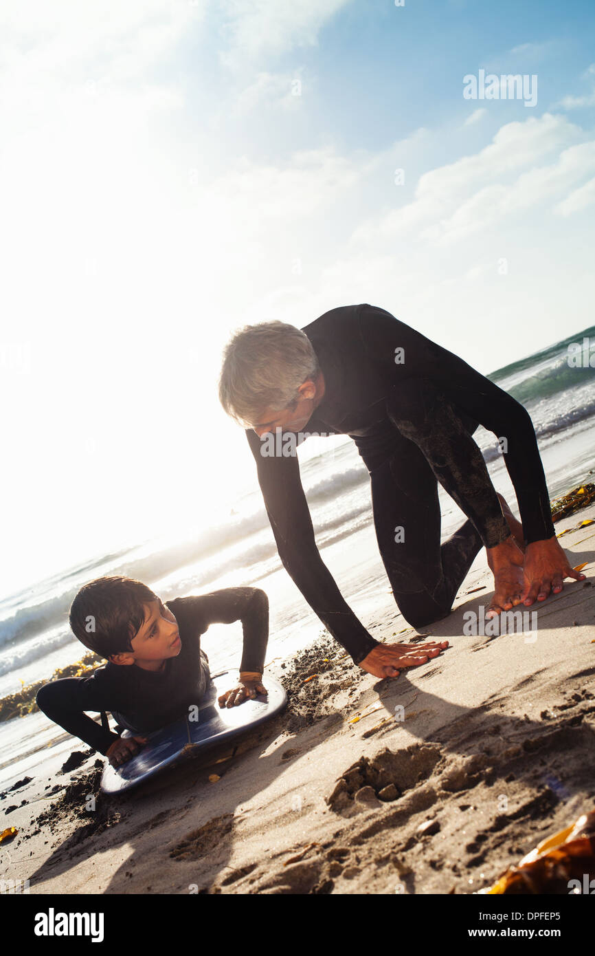 Padre e figlio pratica sulla tavola da surf in spiaggia, Encinitas, CALIFORNIA, STATI UNITI D'AMERICA Foto Stock