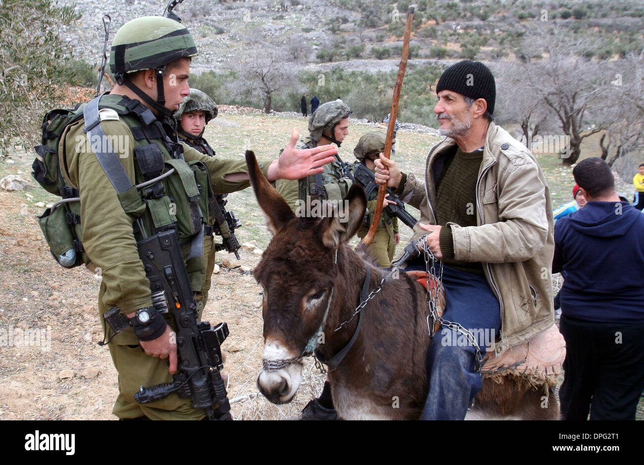 Bulino, West Bank, Territorio palestinese. Xiv gen, 2014. Soldati israeliani formano un buffer tra palestinesi e israeliani in Cisgiordania area tra l'insediamento israeliano di Yitzhar e il villaggio palestinese di Burin, Martedì, 14 gennaio 2014. Gli abitanti del villaggio hanno detto che stavano cercando di aprire una strada sulla loro terra quando un gruppo di coloni ha cercato di fermarli, e l'esercito intervenne. La zona è uno dei punti di attrito tra i militanti i coloni israeliani e palestinesi di credito agli agricoltori: Nedal Eshtayah APA/images/ZUMAPRESS.com/Alamy Live News Foto Stock