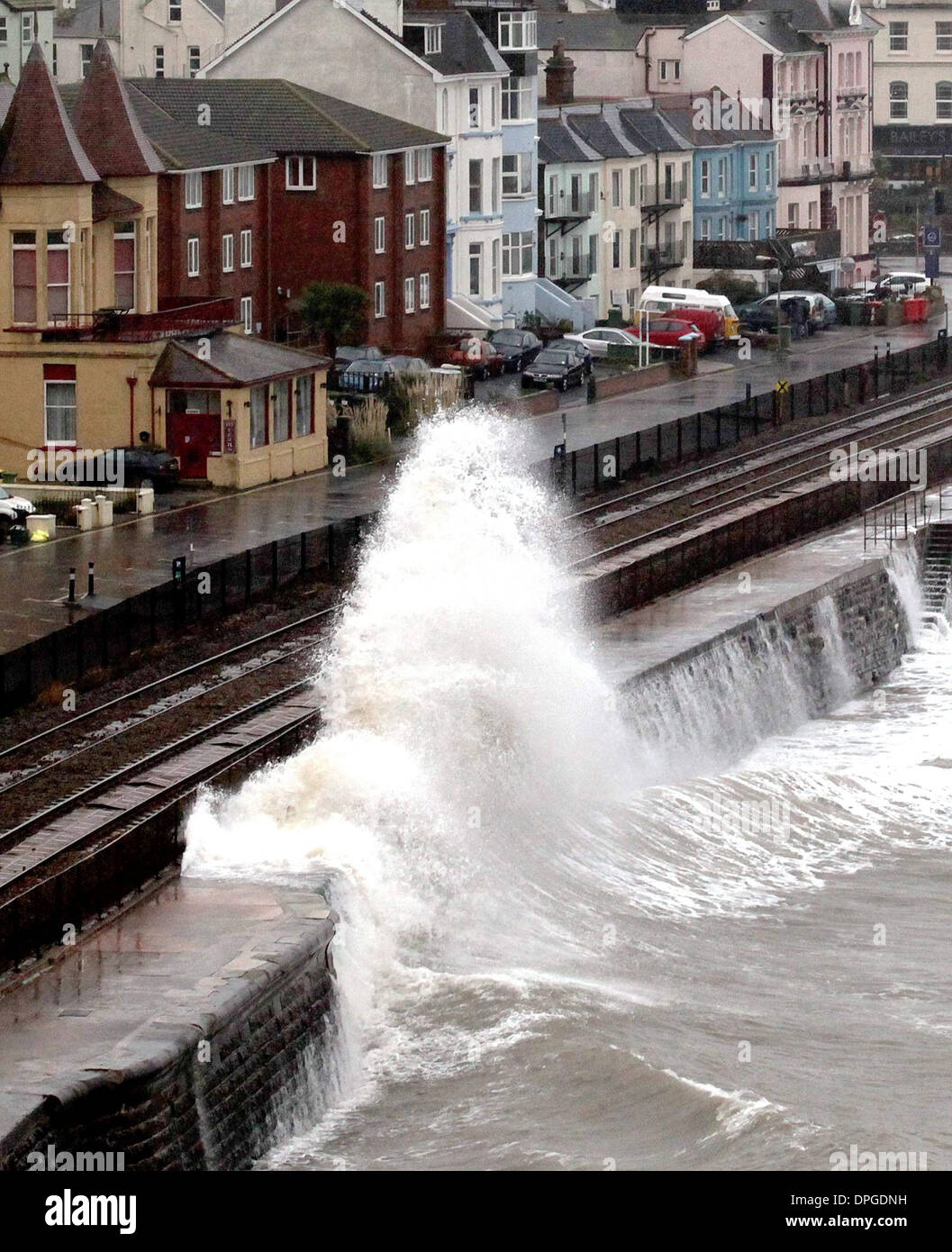 Un treno è martoriata da onde come esso passa attraverso il Dawlish stazione ferroviaria, Devon Foto Stock