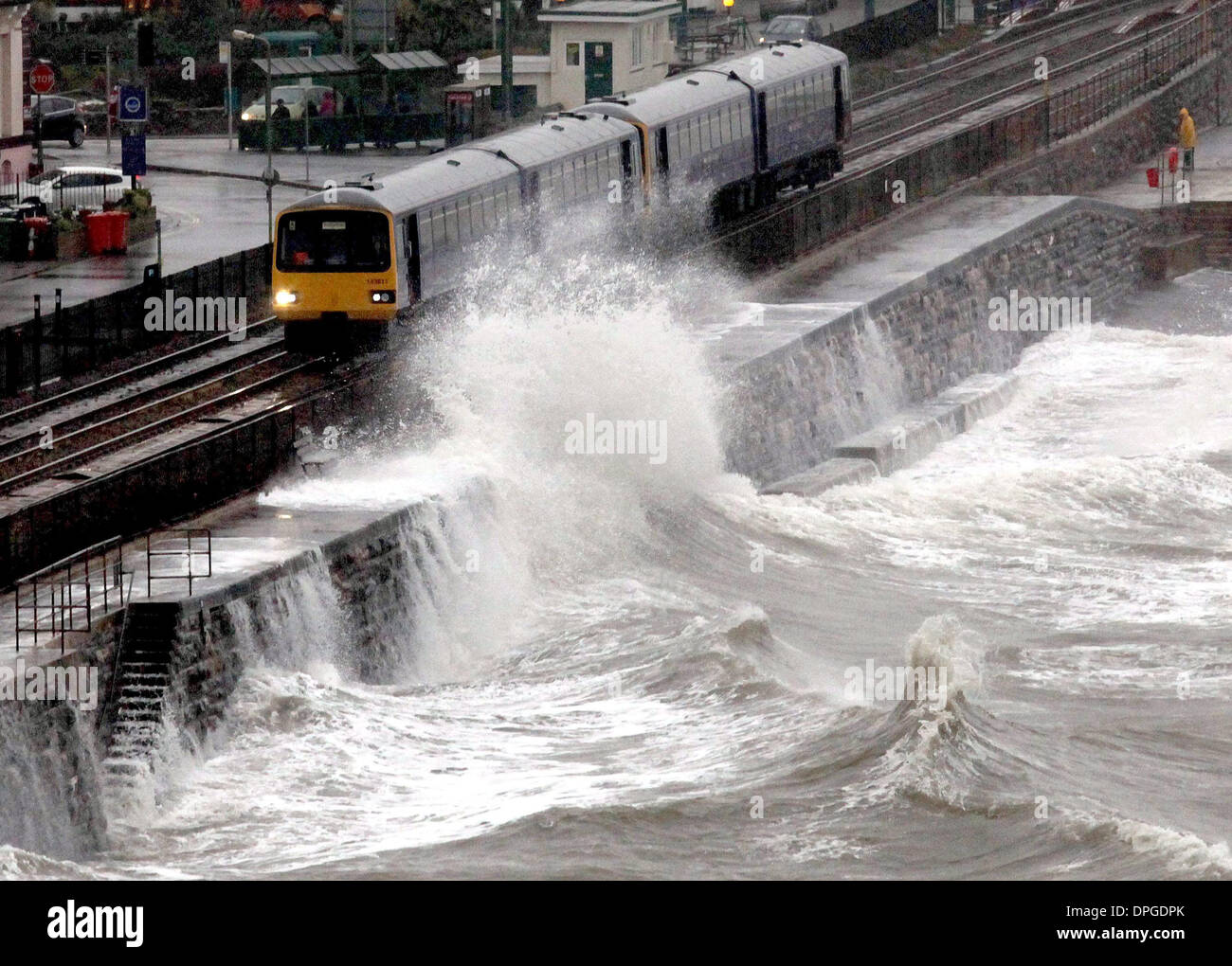 Un treno è martoriata dalle onde come passa attraverso Dawlish stazione ferroviaria Foto Stock