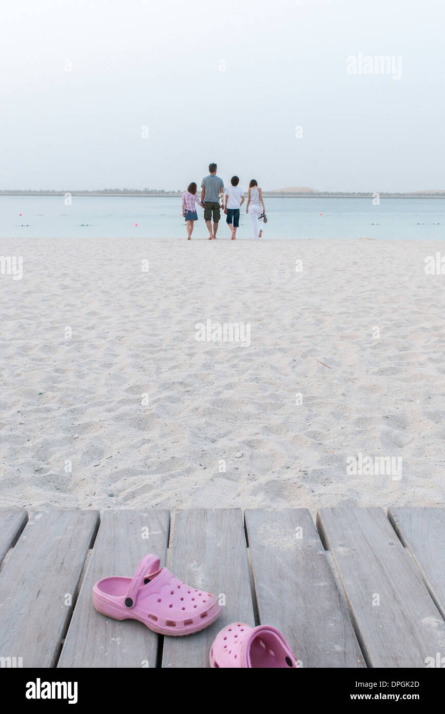 Zoccoli abbandonato sul marciapiede in spiaggia, famiglia avvicinando  l'acqua in background Foto stock - Alamy