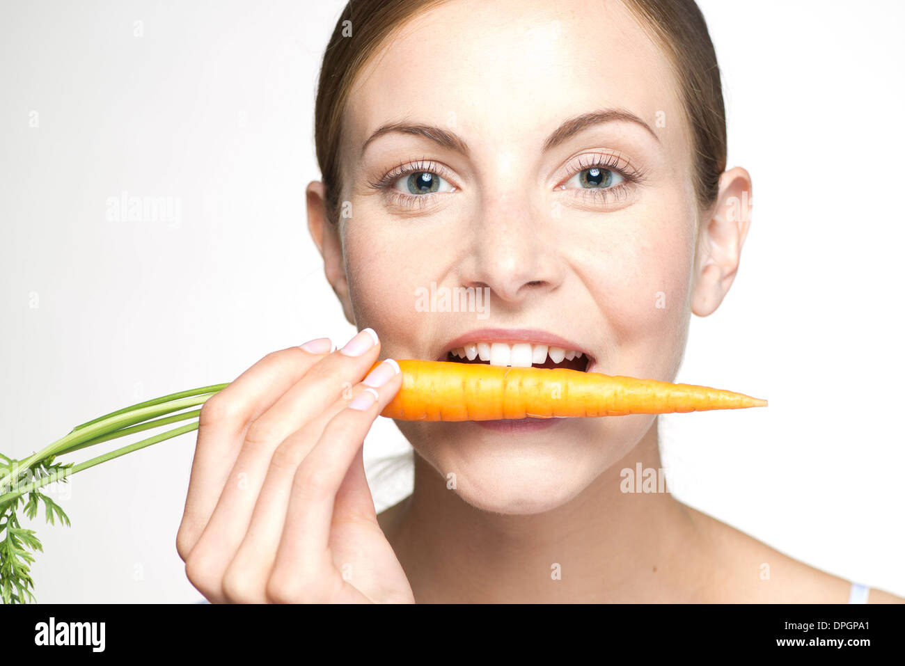 Giovane donna di mordere in carota, ritratto Foto Stock