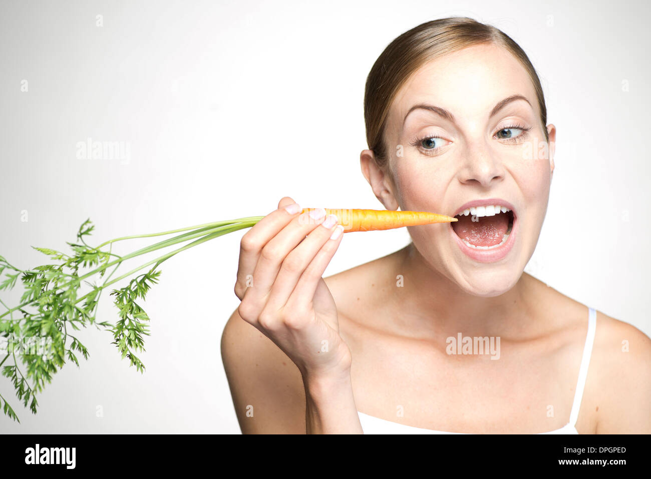 Giovane donna di mangiare la carota Foto Stock
