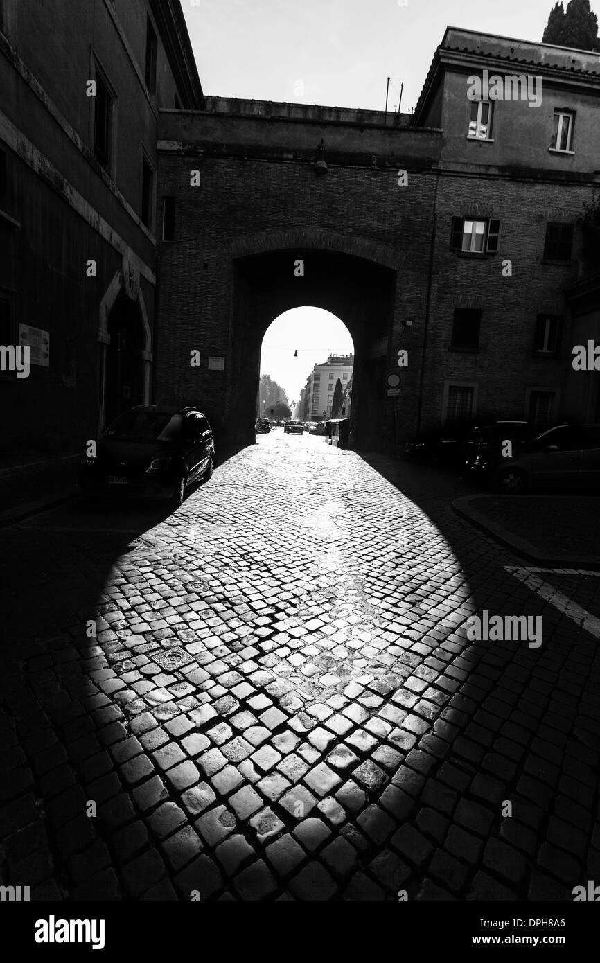 Foto monocromatica di alcune ombre che formano la figura di una suola sporca e usurata di una scarpa, su una strada acciottolata, Roma, Italia. Foto Stock