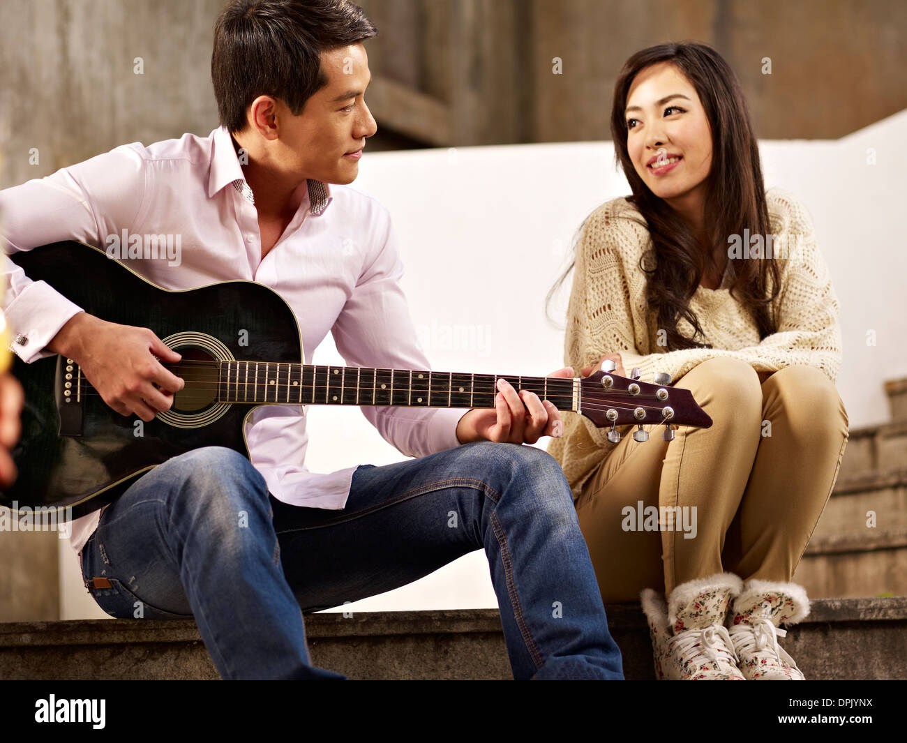 Giovane uomo a suonare la chitarra per ragazza Foto Stock